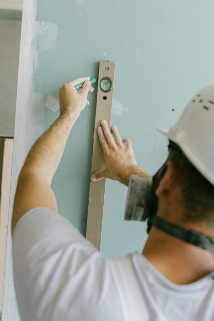 A person marking a chalk line on the floor before tiling a bathroom wall.