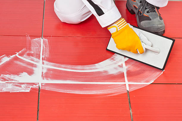 A person spreading grout between tiles on a floor.