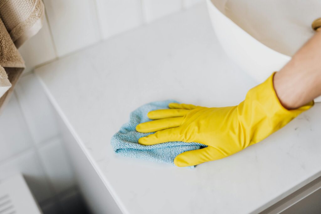 A person wiping down a marble countertop with a microfiber cloth.