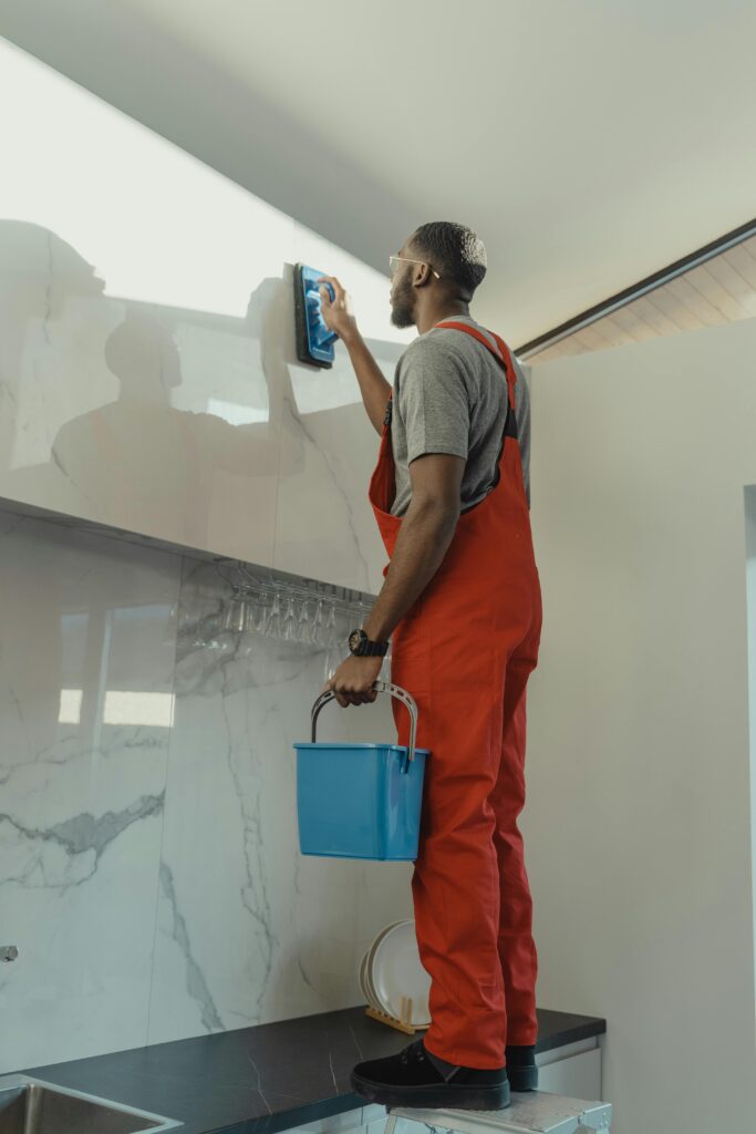 A person scrubbing grout lines between tiles with a specialized grout cleaning brush.