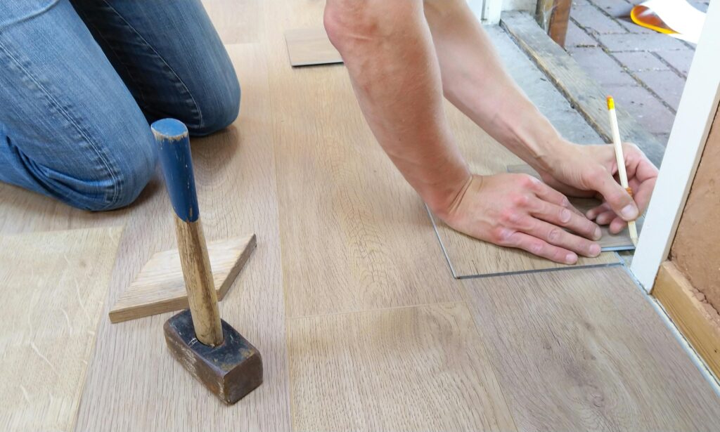 A person installing laminate flooring as a DIY project.