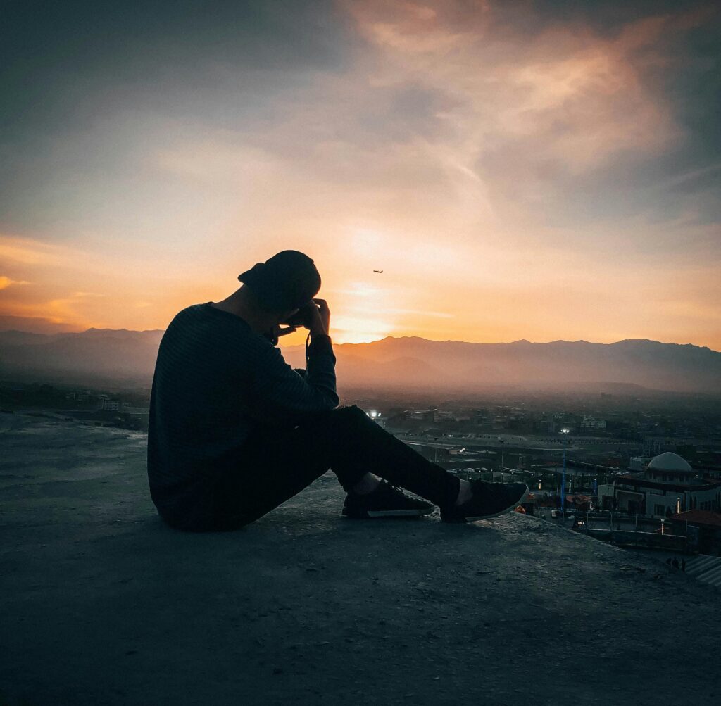 A serene landscape with a person sitting on a bench, watching the sunrise